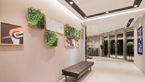 A modern lobby with a bench, wall-mounted greenery, and abstract art. - Homeinn Selected Hotel (Shanghai Convention Center Qibao Metro Station) (Shanghai)