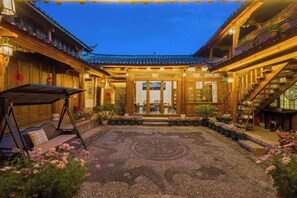 A traditional courtyard with a central seating area, a wooden building with a tiled roof, and a well-maintained garden.