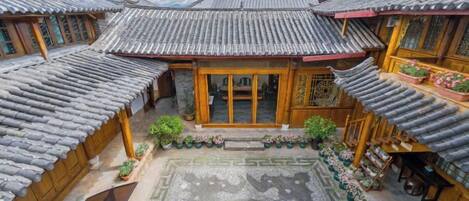 Un patio tradicional con tejados de baldosas, edificios de madera y plantas en macetas.