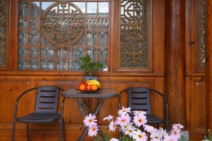 Ein Holzinnenraum mit einem Tisch, zwei Stühlen, einer Blumenvase und einem Fenster mit dekorativen Verzierungen.