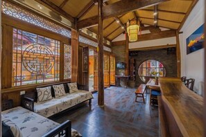 Ein traditionelles Interieur mit Holzbalken, einer Couch, einem Esstisch und einer Bar.