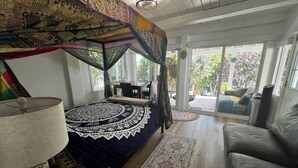 A bedroom with a canopy bed, a sitting area with a sofa, and a view of the outdoors.