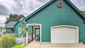 A two-story house with a green exterior, a white garage door, and a covered porch.