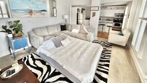 A modern living room with a sofa, a bed, a dining area, and a kitchen.