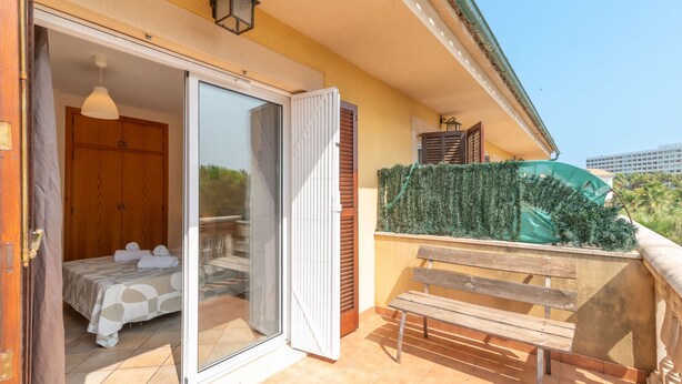 A balcony with a bed, a bench, and a green hedge. - Villa Lago for 5 people with community pool (Puerto de Alcudia)