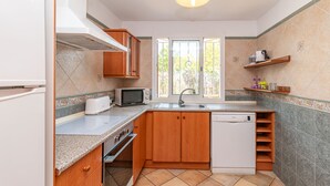 A compact kitchen with wooden cabinets, a microwave, a toaster, and a dishwasher. - Villa Lago for 5 people with community pool (Puerto de Alcudia)