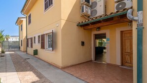A yellow building with a tiled entrance and a green awning. - Villa Lago for 5 people with community pool (Puerto de Alcudia)