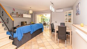 A modern living room with a sofa, a dining table, and a staircase. - Villa Lago for 5 people with community pool (Puerto de Alcudia)