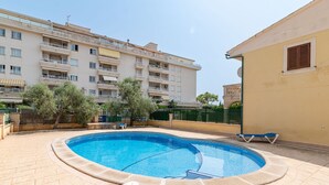 A swimming pool with a tiled deck, surrounded by a low fence and trees. - Villa Lago for 5 people with community pool (Puerto de Alcudia)