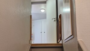 Un escalier avec une rampe, menant à une porte dotée d’une poignée.