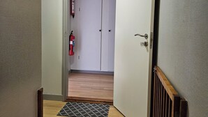Un couloir doté d’un plancher en bois, d’un extincteur fixé au mur et d’une porte donnant sur une autre pièce.