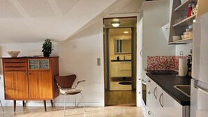 Une cuisine moderne avec un plancher en bois, des armoires blanches et un coin repas comprenant une chaise et un buffet.