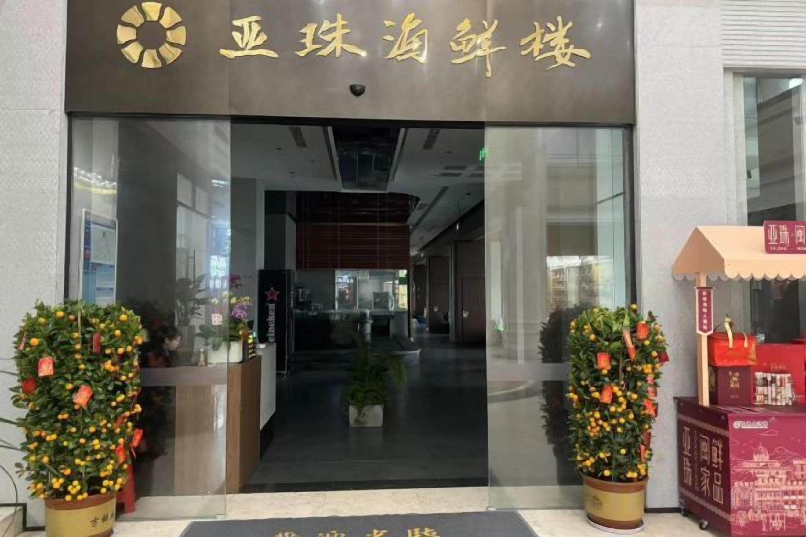 A hotel entrance with a reception desk, potted plants, and a sign above the door.