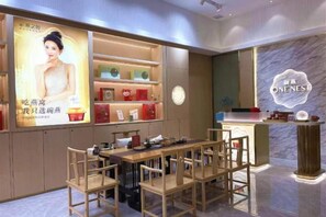 A hotel lobby with a reception desk, seating area, and a wall with a logo. - Haomei International Hotel (Anxi Government Store) (Anxi)