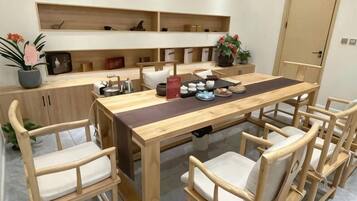 Un coin repas avec une table et des chaises en bois, un espace cuisine avec des étagères et une plante en pot.