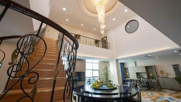 A spacious lobby with a grand staircase, a chandelier, and a round dining table with chairs. - Haomei International Hotel (Anxi Government Store) (Anxi)