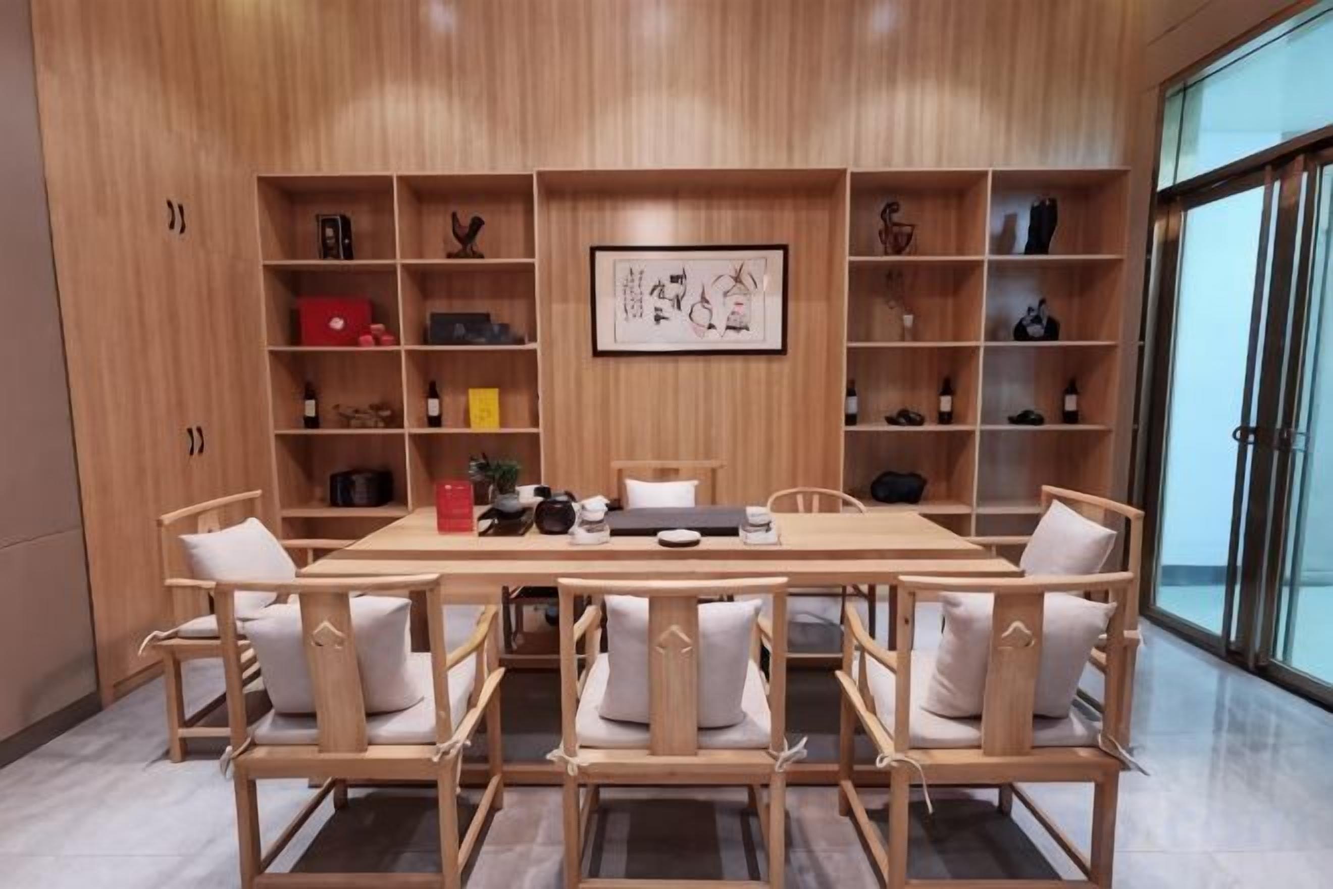 A dining area with a wooden table and chairs, surrounded by shelves with various items.