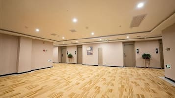 A large, empty conference room with a patterned carpet, beige walls, and recessed lighting.