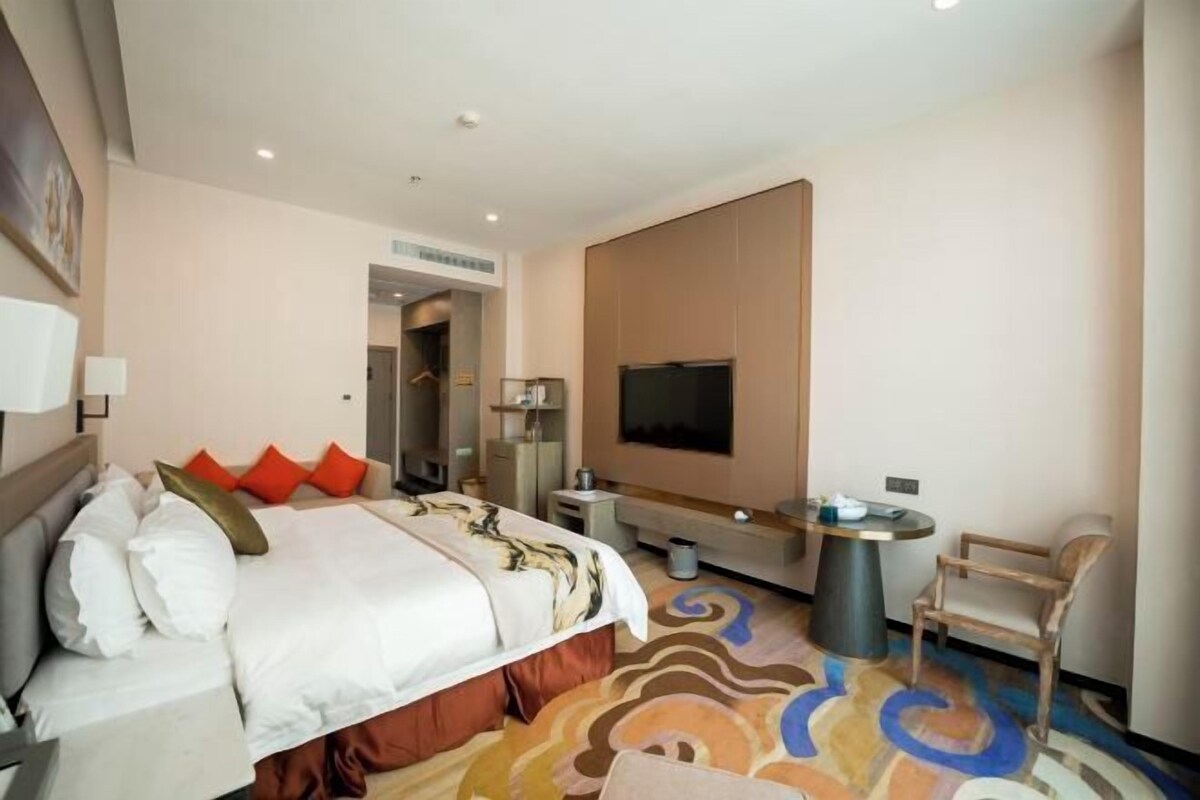 A hotel room with a bed, a TV, a desk, and a chair.