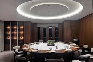 A conference room with a round table, chairs, and a modern ceiling light fixture.