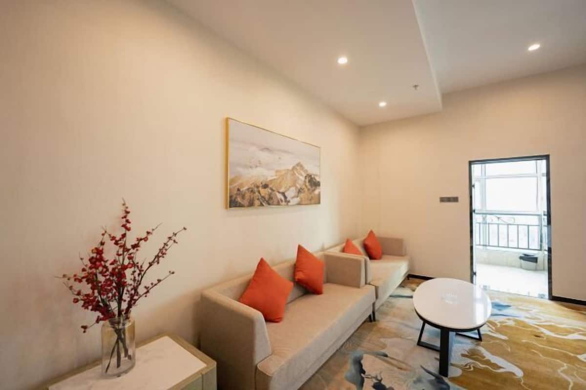 A modern hotel lobby with a sofa set, a vase with red flowers, a painting on the wall, and a round table.