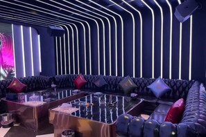A modern lounge area with a curved sofa and a glass coffee table, featuring a unique ceiling design with vertical lines. - Haomei International Hotel (Anxi Government Store) (Anxi)