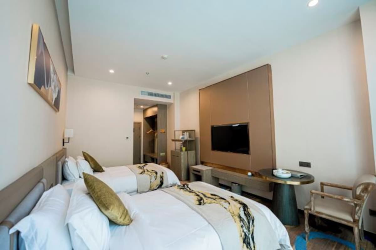 Una habitación de hotel con una cama grande, televisión, escritorio y una silla.