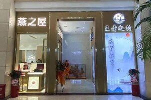 Entrada de hotel con mostrador de recepción, un ventanal con vistas y un cartel con caracteres chinos.