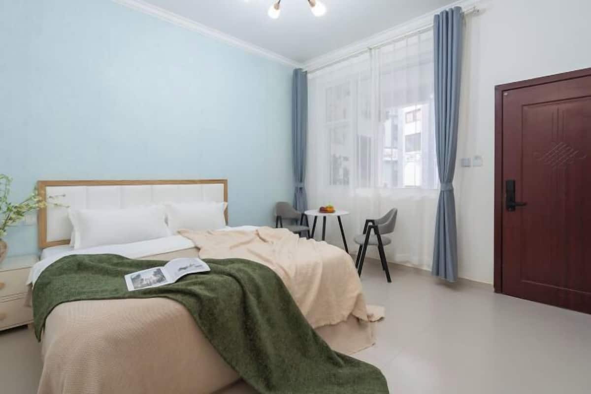 Une chambre à coucher comprenant un lit, une table de chevet, une chaise et une petite table sur laquelle est posée une plante.