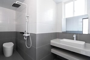 A modern bathroom with a shower, a toilet, a sink, and a mirror.