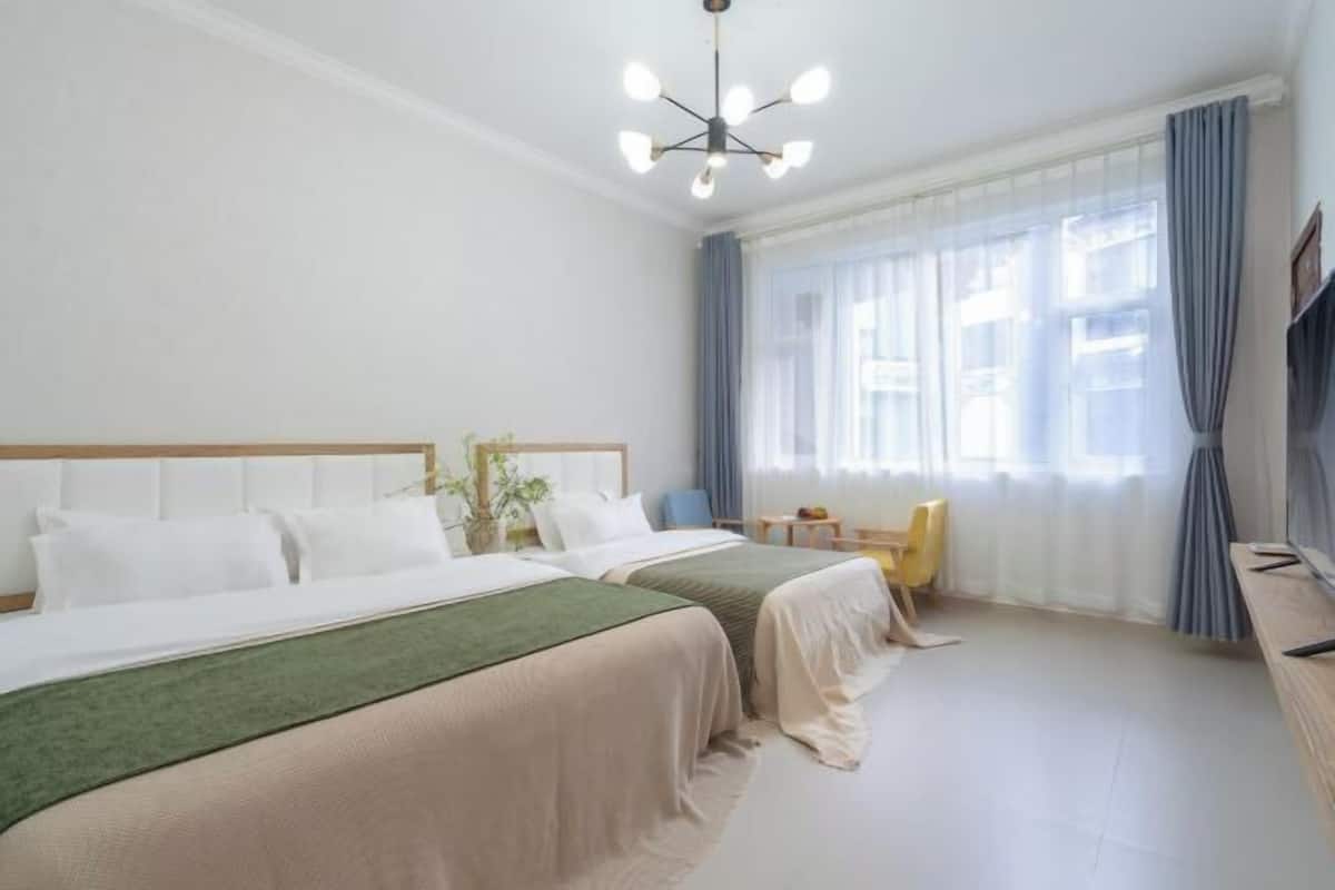 Une chambre d’hôtel avec deux lits, une télévision, un bureau et une fenêtre avec des rideaux.