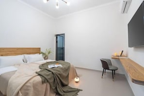 A modern bedroom with a bed, bedside table, chair, and a TV mounted on the wall.