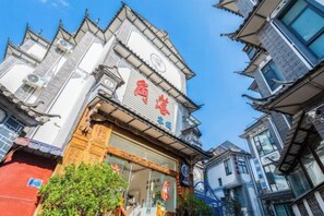 A traditional building with a prominent red sign, multiple windows, and a tiled roof. - Corner Inn (Dali City)