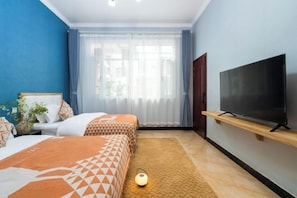 A hotel room with two beds, a TV, a window with curtains, and a lamp on the floor.