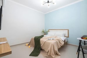 A bedroom with a bed, bedside table, and a small table with fruits.