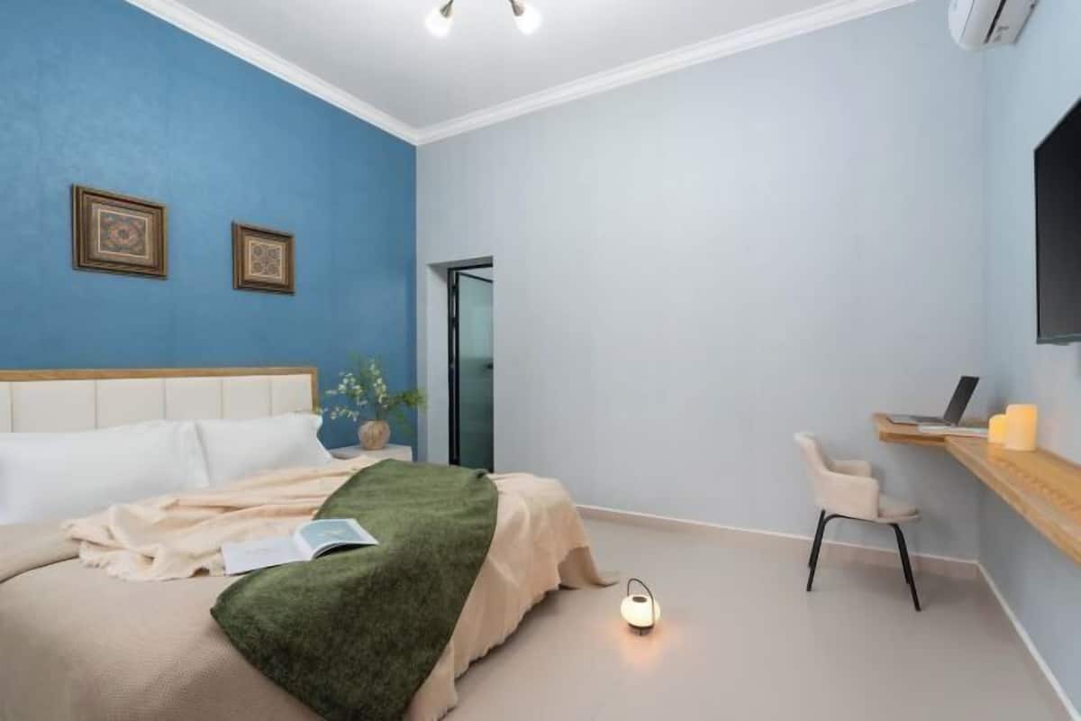 Une chambre à coucher comprenant un lit, une table de chevet, une chaise et un bureau avec un ordinateur portable.