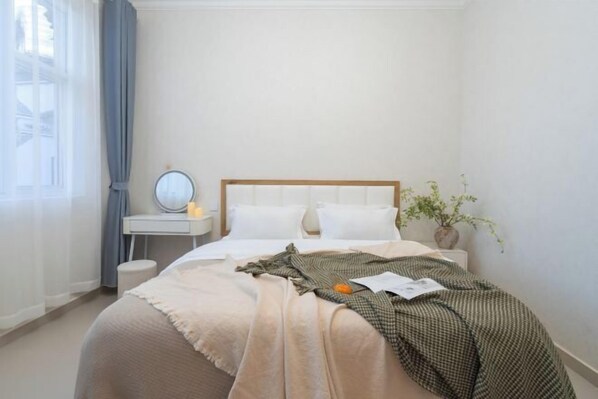 A neatly arranged bedroom with a bed, bedside table, and a potted plant.