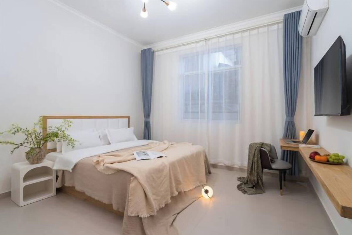 Une chambre d’hôtel moderne équipée d’un lit, d’une table de chevet, d’un bureau, d’une chaise et d’un téléviseur à écran plat.