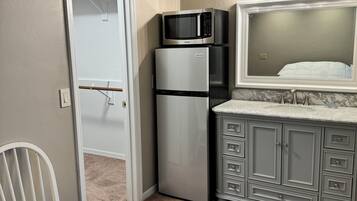 Efficient kitchenette area with microwave and refrigerator, perfect for compact living spaces.