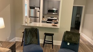 A modern kitchen with a built-in microwave, refrigerator, and oven. There are two blue chairs with green throw pillows and a small table with a lamp. - Deluxe 2700 sqft 3 bed 4 bath Villa in Boone, NC (Boone)