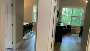 A spacious hallway with hardwood flooring, leading to a room with a large window and a view of trees. - Deluxe 2700 sqft 3 bed 4 bath Villa in Boone, NC (Boone)