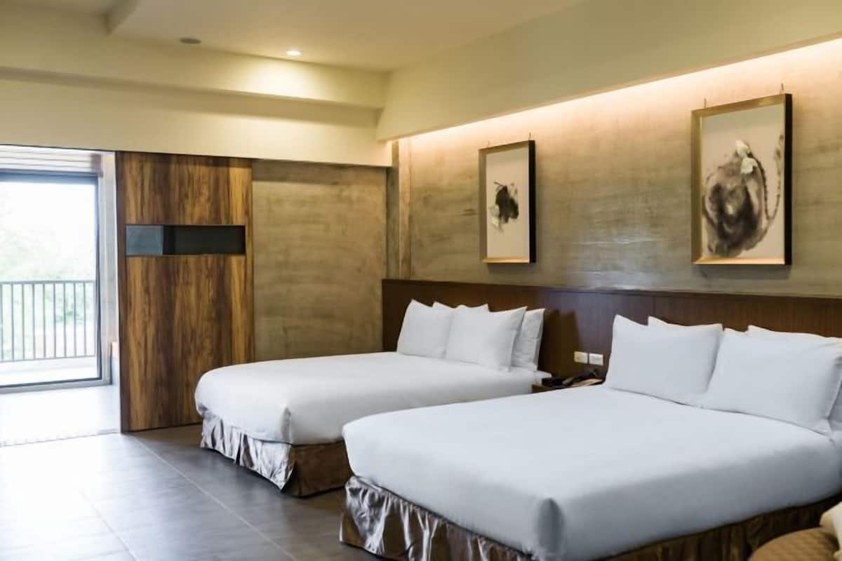 A hotel room with two beds, a wooden accent wall, and artwork.