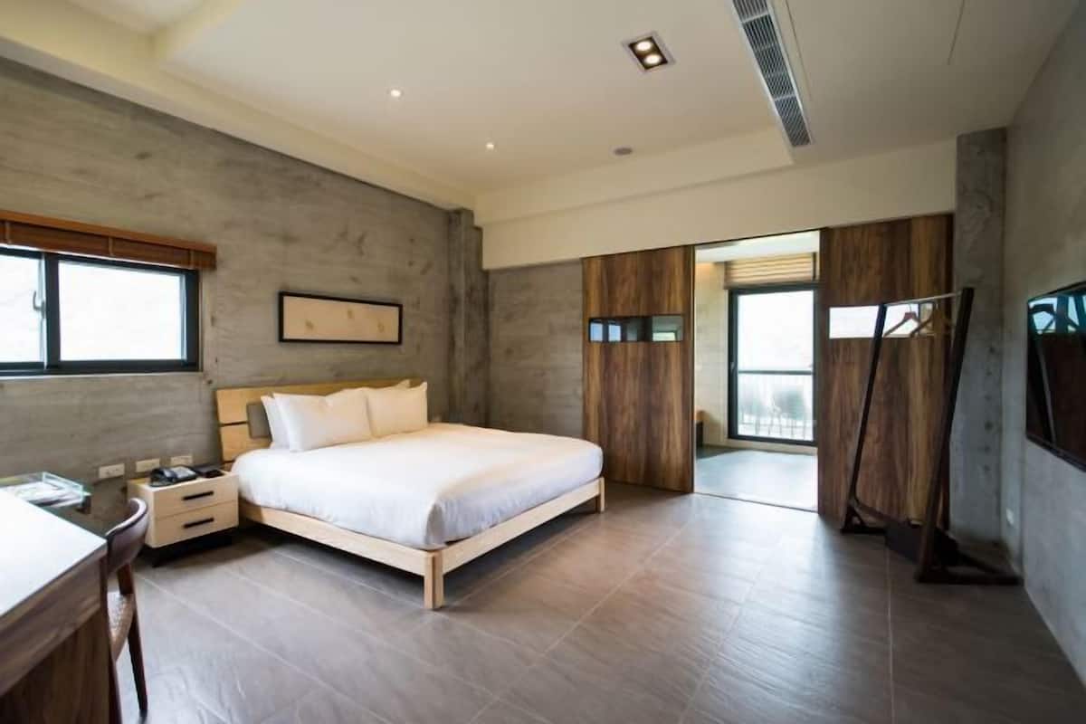 A modern bedroom with a wooden bed, a desk, and a wardrobe.