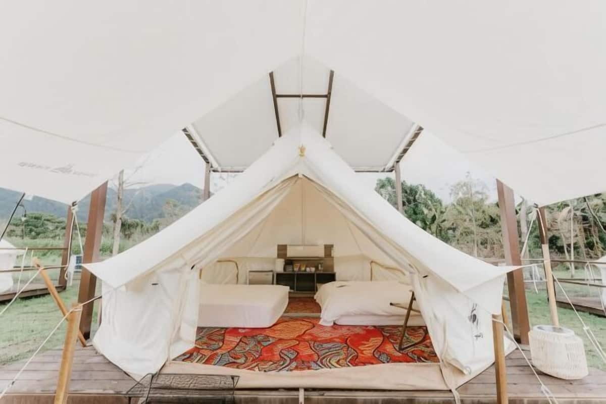 A tent with a bed, a table, and a rug.