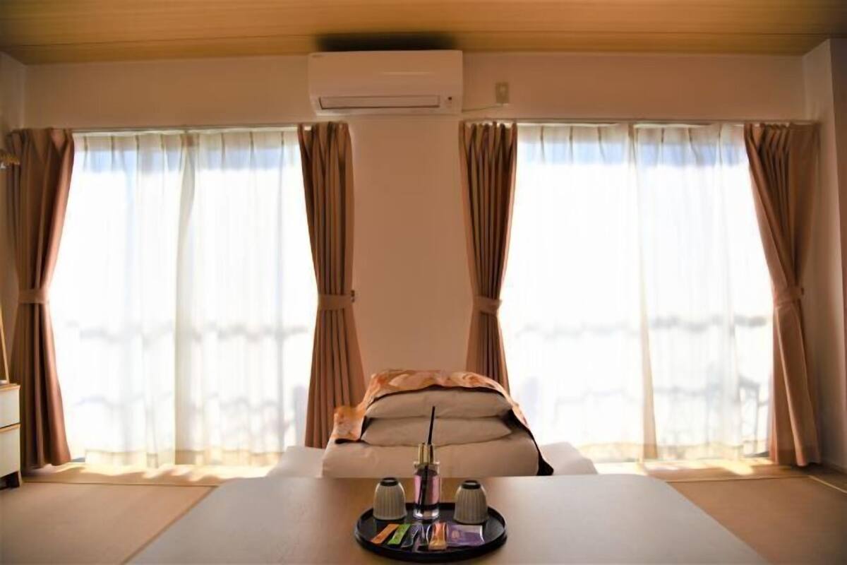 Een hotelkamer met een bed, een nachtkastje, een airconditioning en gordijnen.