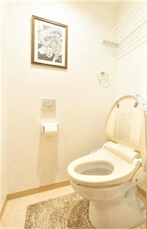 A bathroom with a toilet, a framed picture on the wall, a hand dryer, and a paper towel dispenser. - U-shuku Kyoto Fushimi (Kyoto)