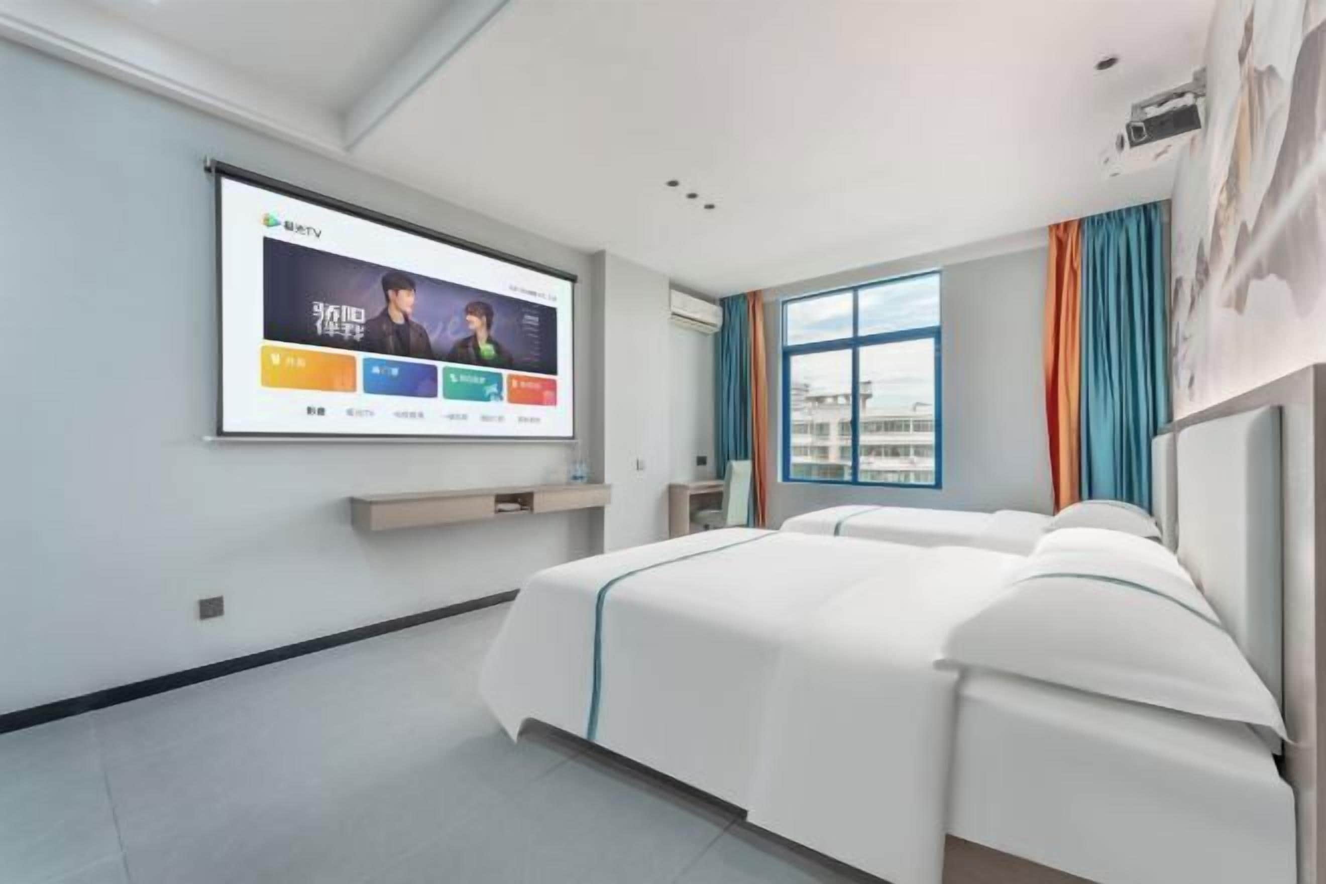 A modern hotel room with a large bed, a TV mounted on the wall, and a window with curtains.