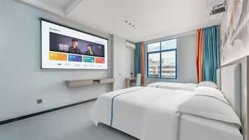 A modern hotel room with a large bed, a TV mounted on the wall, and a window with curtains.