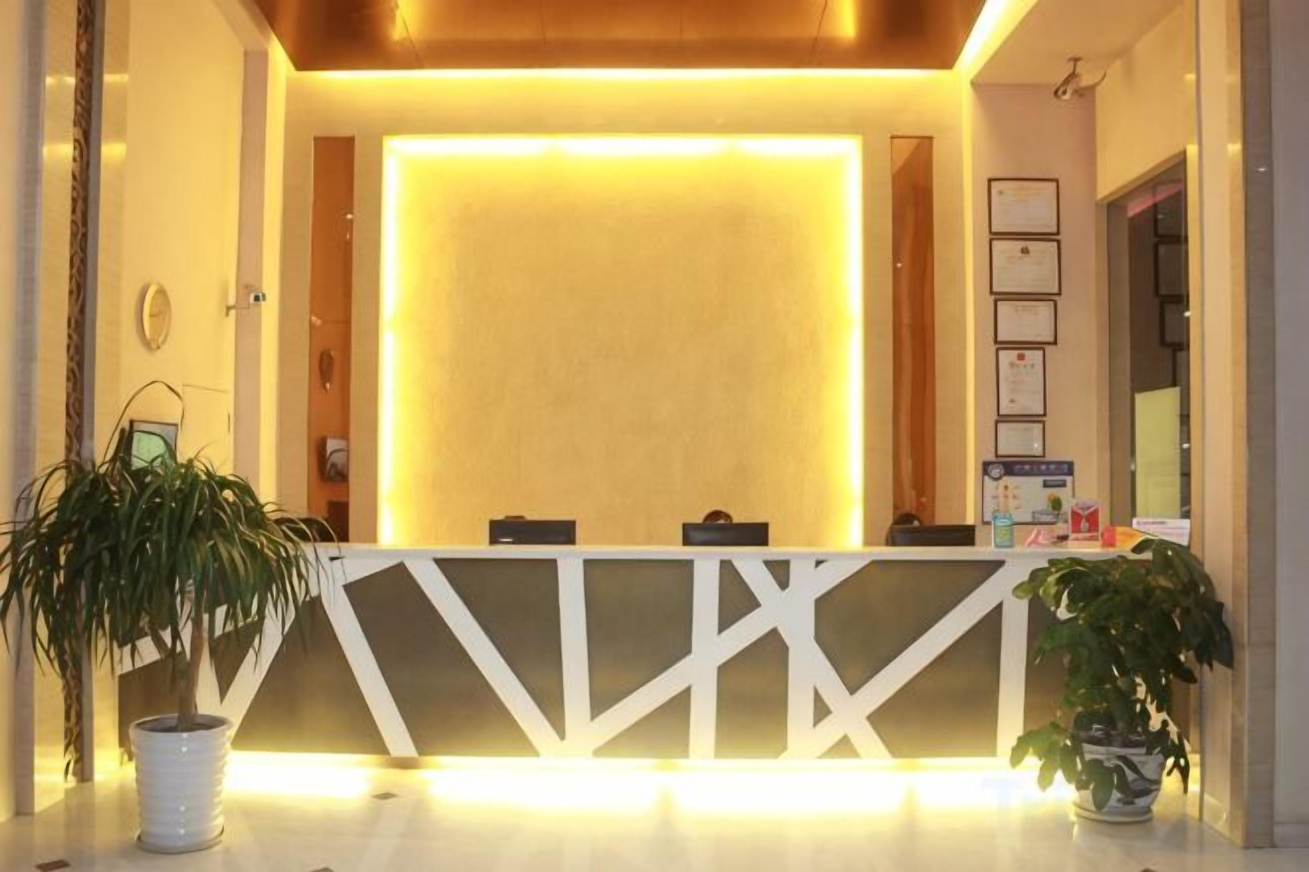 A reception desk with a modern design, a potted plant, and framed certificates on the wall.