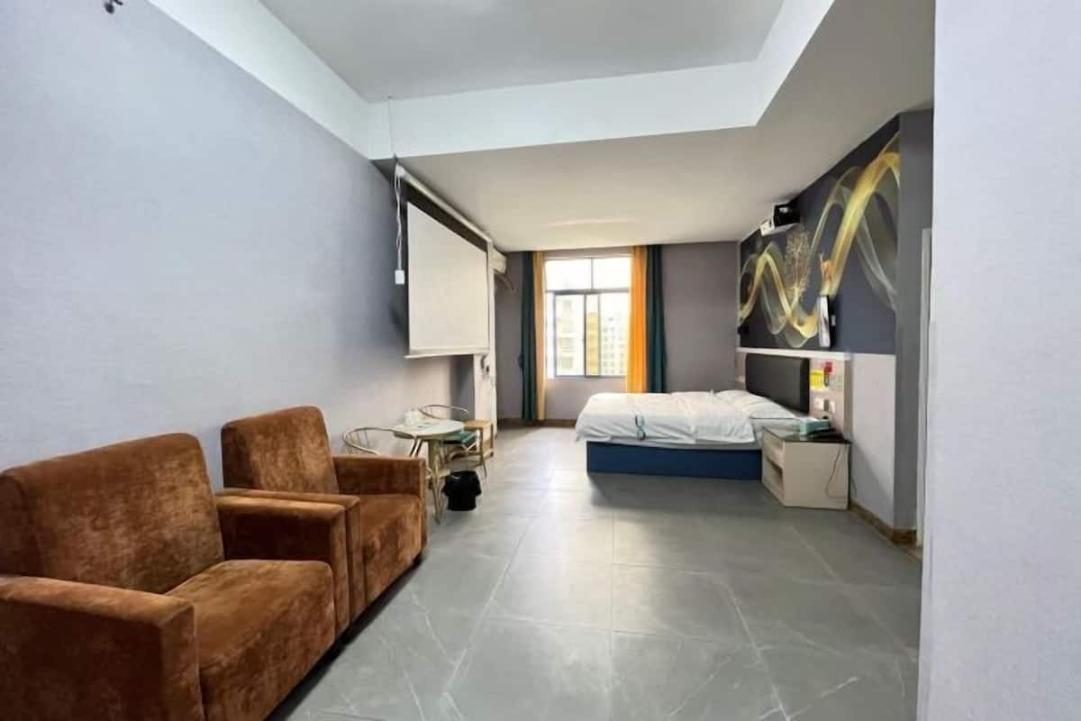 A room with a bed, a sofa, a desk, a chair, a window, and a painting on the wall.